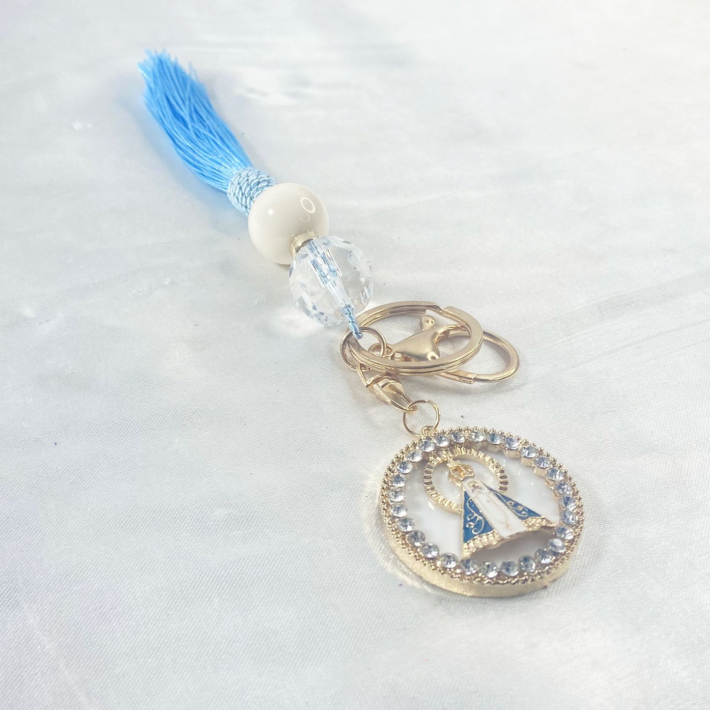 CHAVEIRO LUXO COM MOSQUETE NOSSA SENHORA APARECIDA COM POMPOM AZUL BEBÊ (1 UNIDADE)