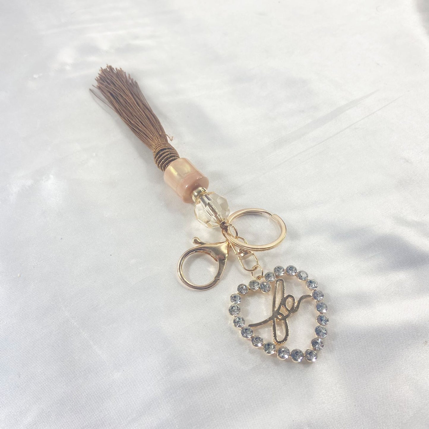 CHAVEIRO LUXO COM MOSQUETE FÉ CORAÇÃO COM POMPOM CARAMELO (1 UNIDADE)