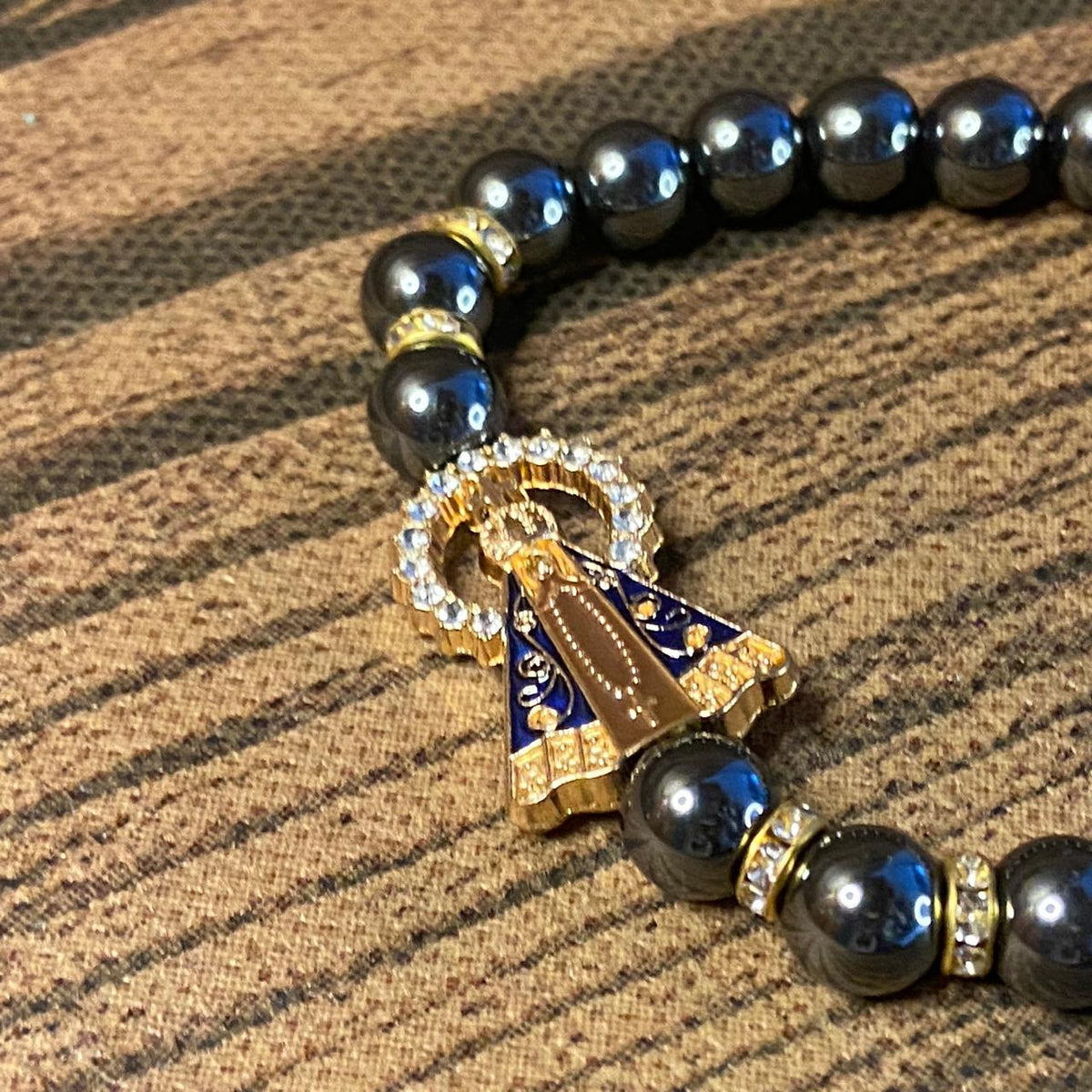 PULSEIRA HEMATITA NOSSA SENHORA APARECIDA COM PINGENTE DE CRUZ  08MM (06 UNIDADES)