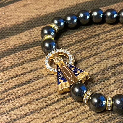 PULSEIRA HEMATITA NOSSA SENHORA APARECIDA COM PINGENTE DE CRUZ  08MM (06 UNIDADES)