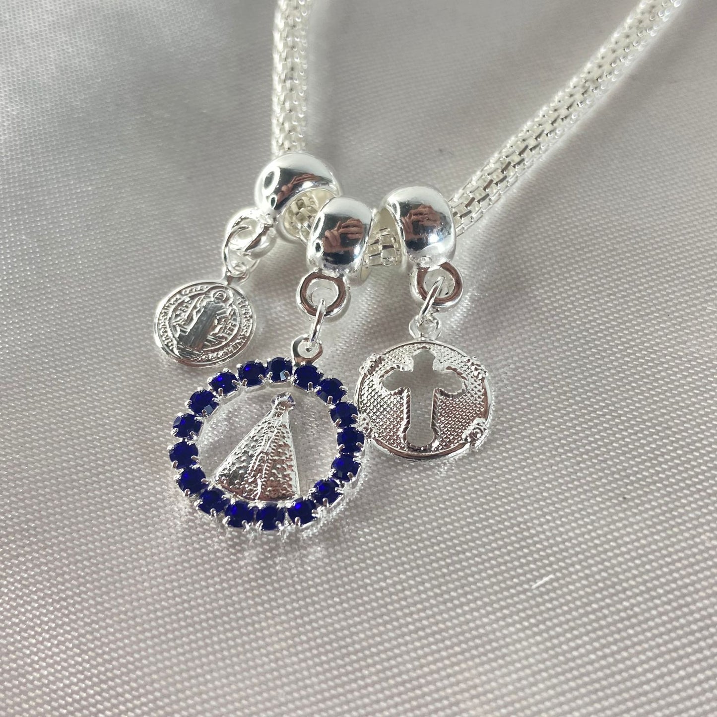 PULSEIRA NÍQUEL REDONDO NOSSA SENHORA APARECIDA COM STRASS AZUL (6 UNIDADES)