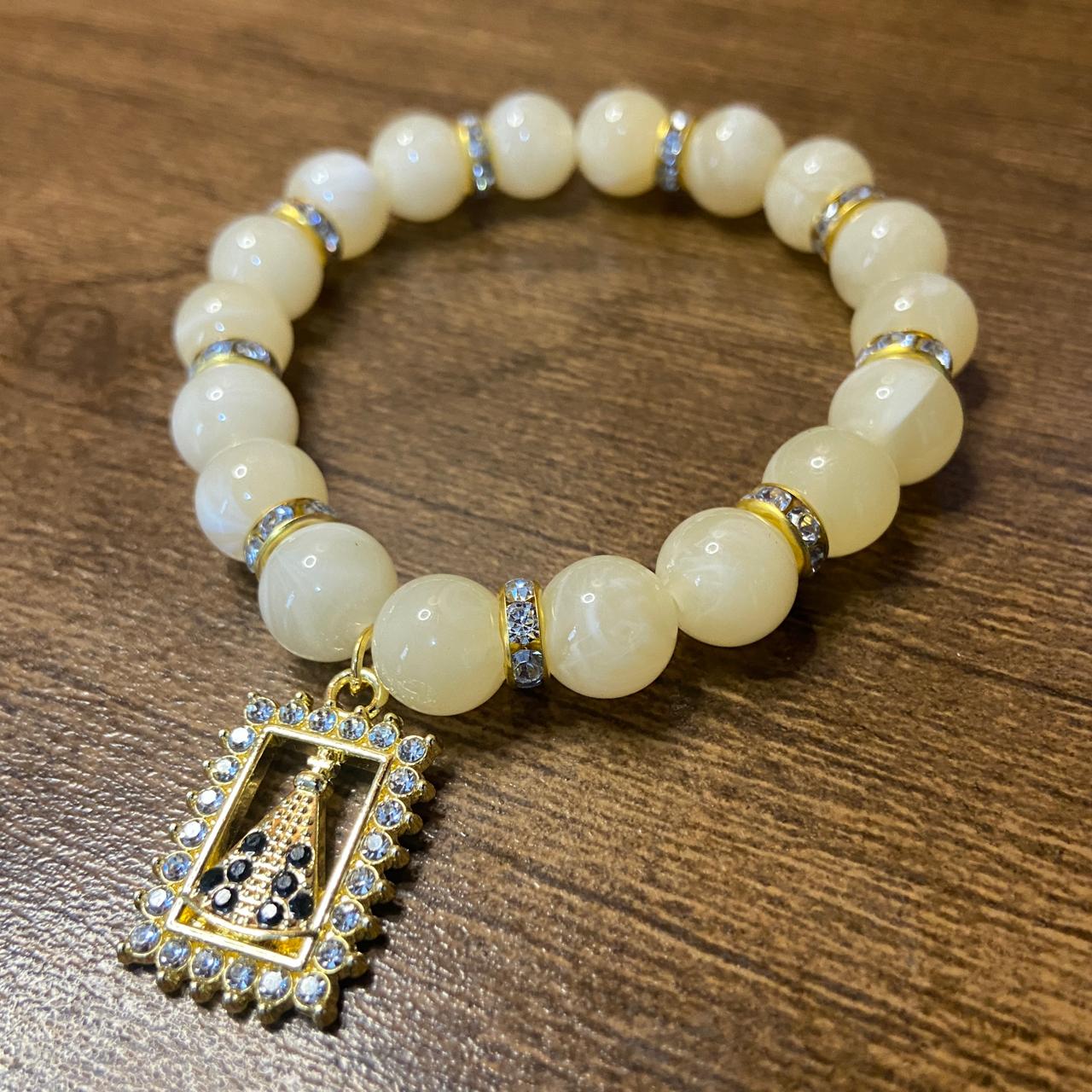 PULSEIRA PÉROLA BEGE COM PINGENTE NOSSA SENHORA APARECIDA COM STRASS 08MM  (03 UNIDADES)
