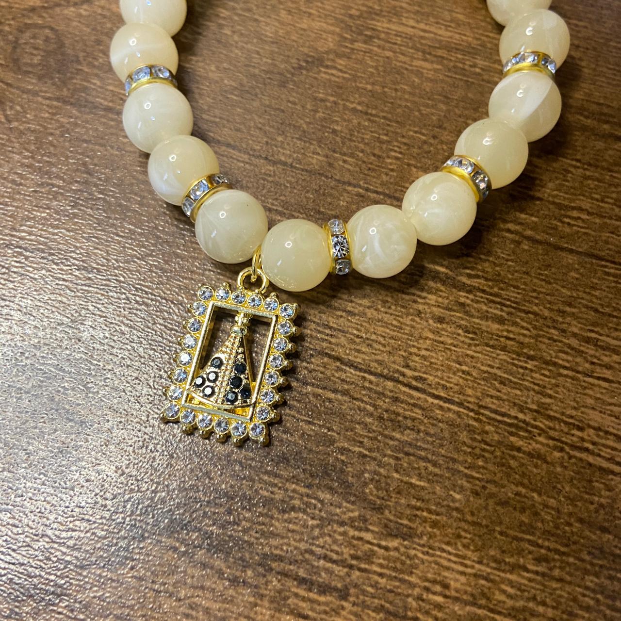 PULSEIRA PÉROLA BEGE COM PINGENTE NOSSA SENHORA APARECIDA COM STRASS 08MM  (03 UNIDADES)