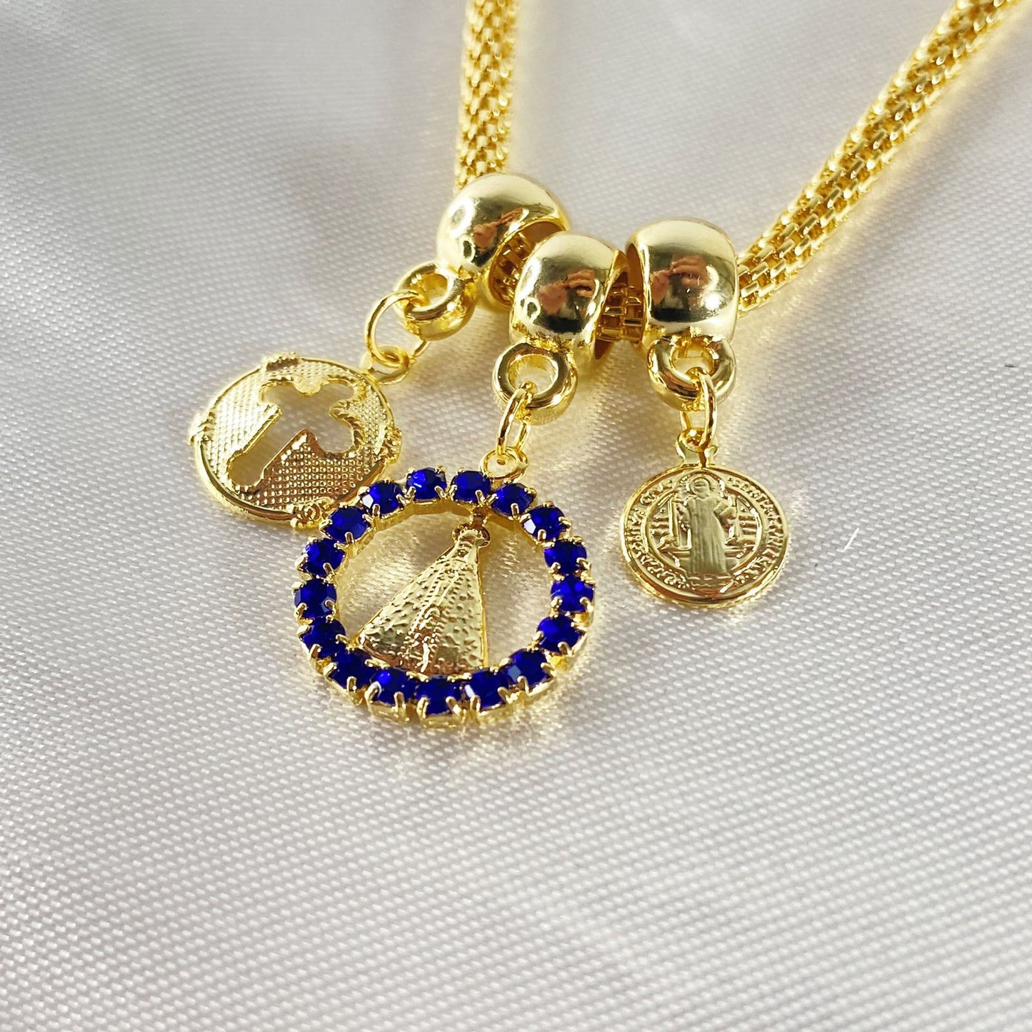 PULSEIRA DOURADA REDONDA NOSSA SENHORA APARECIDA COM STRASS AZUL  (6 UNIDADES)